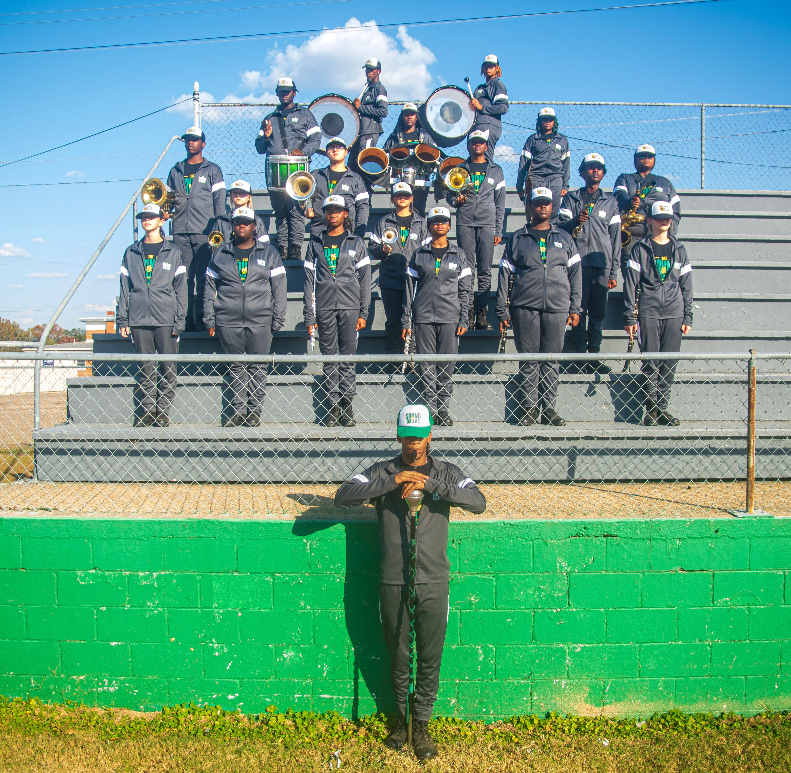 Marching band members in uniform posing on bleachers and field.