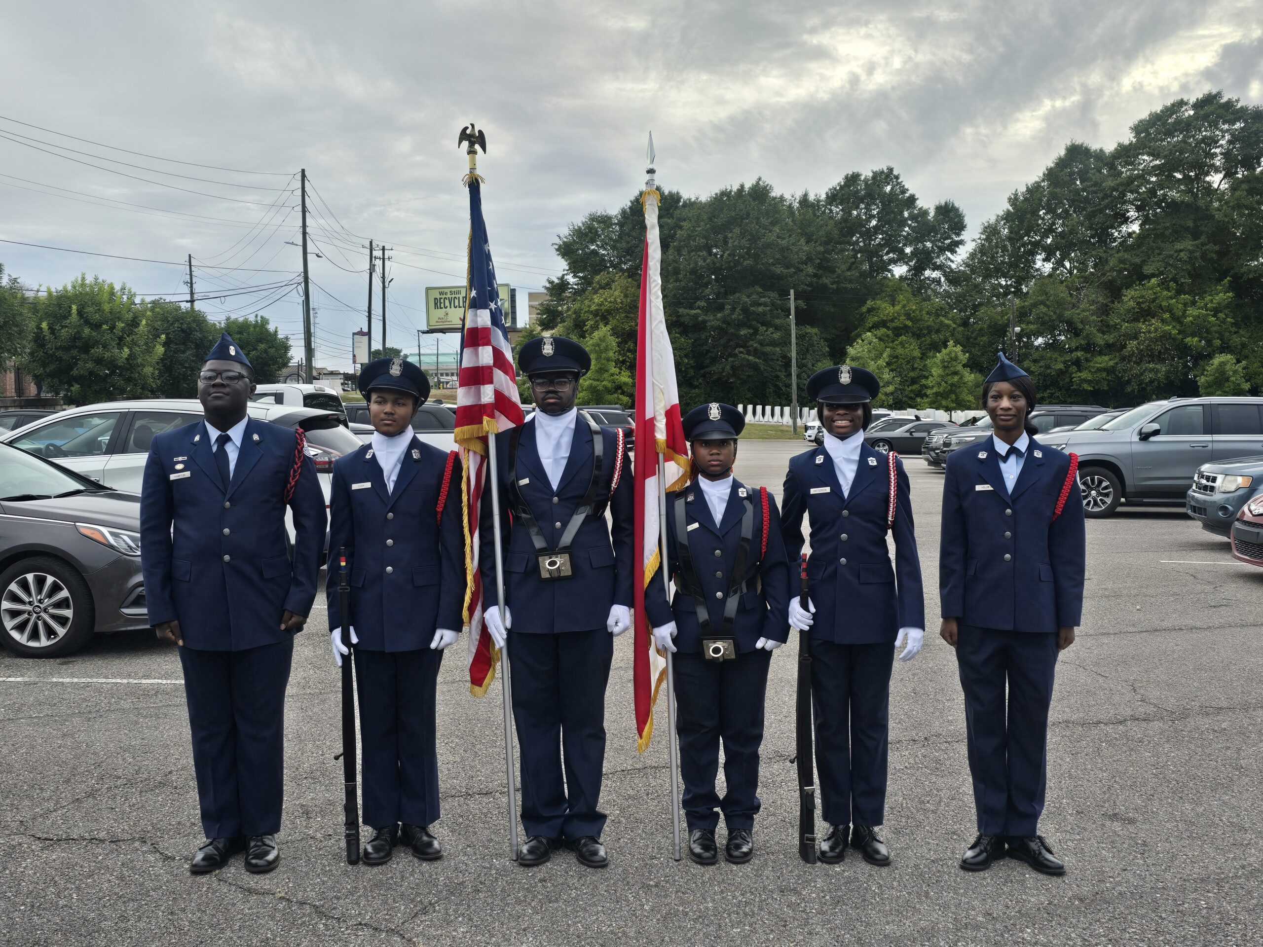 Group of uniformed men holding flags in an outdoor setting.