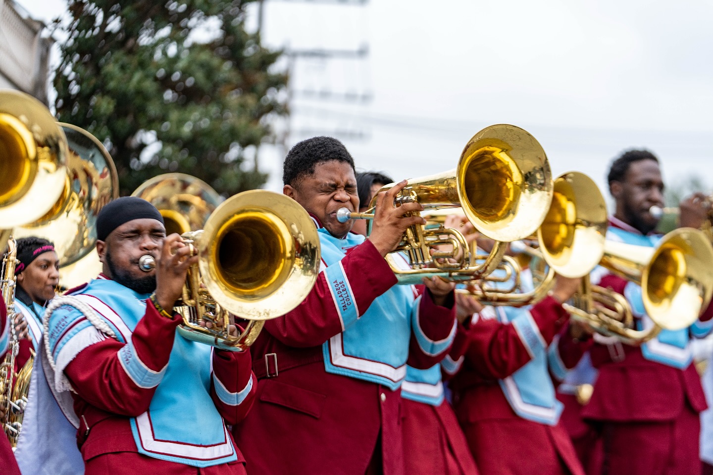 Marching band members play brass instruments in uniform.