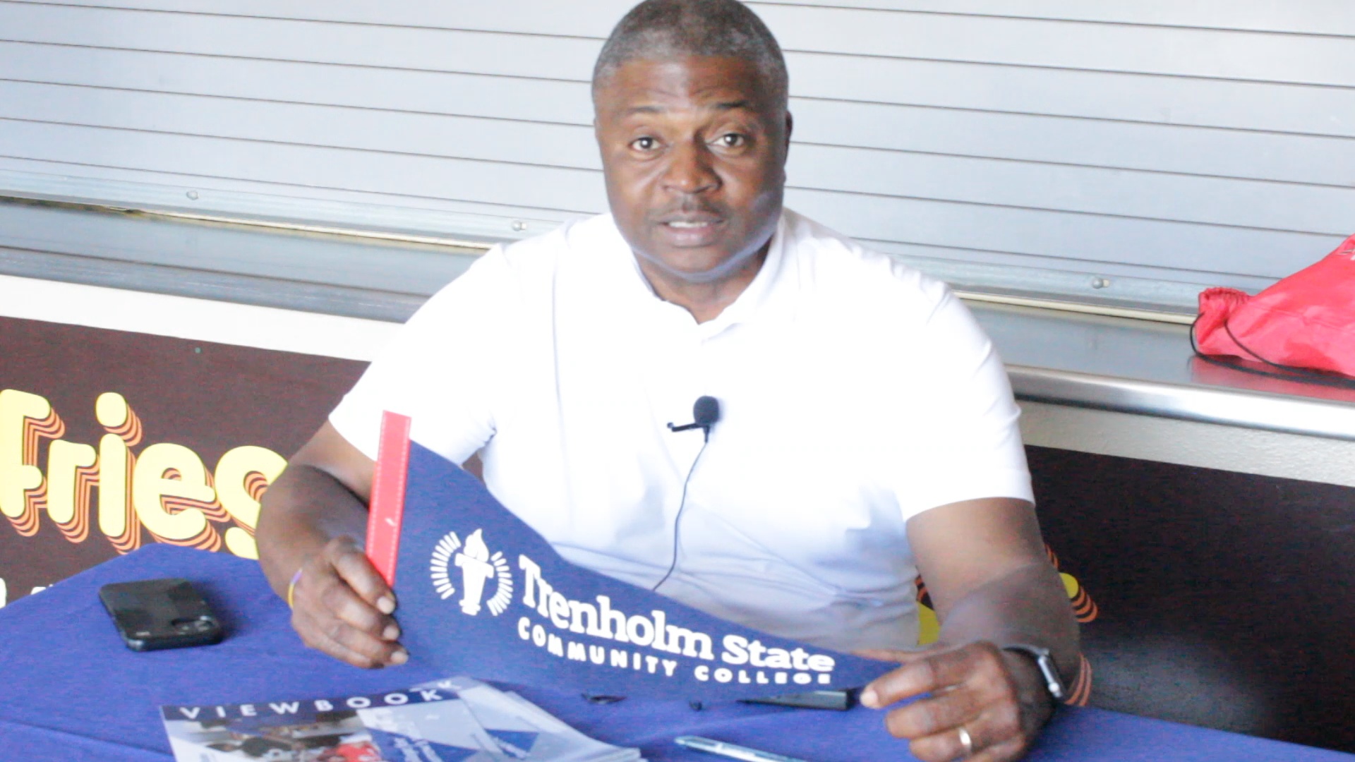Man in white shirt holding a blue Menholm Bible booklet.