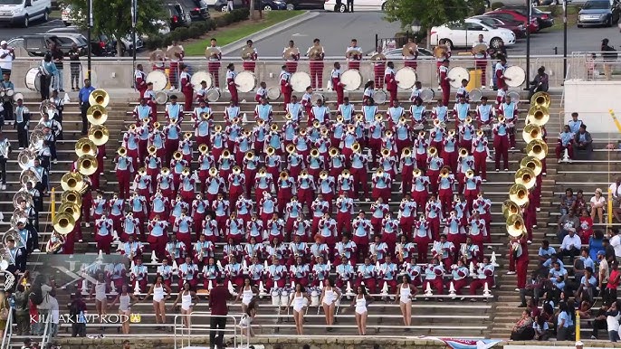 Large marching band performing on bleachers in uniform.