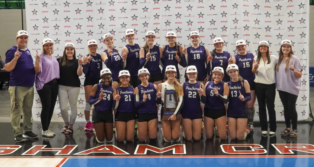 A high school volleyball team posing for a group photo on the court.